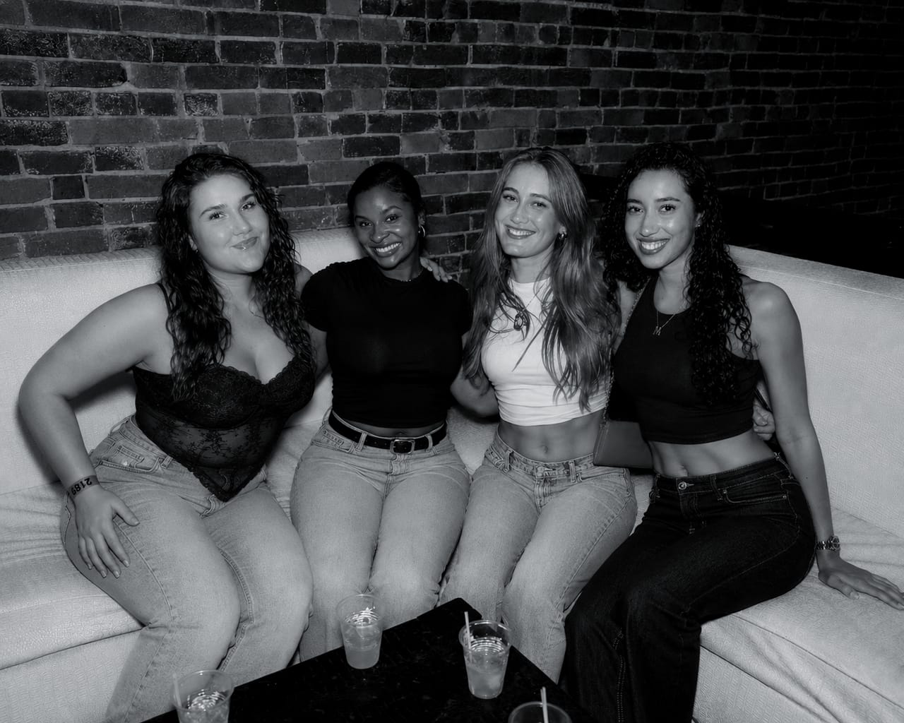 A group of guests seated together in a reserved section at CTRL against the venue's exposed brick wall.
